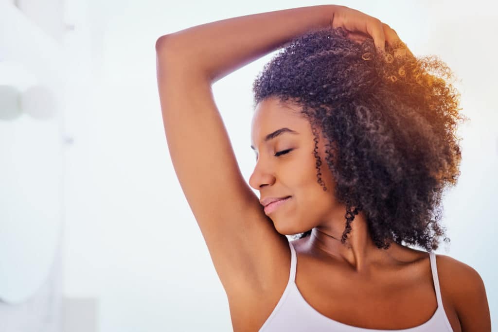An image of a Beautiful Black woman with her arm above her head showing her hairless armpits 