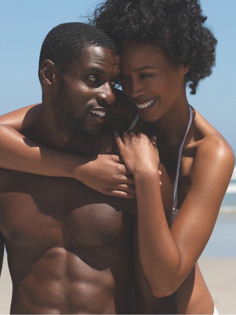 woman holding man from behind at the beach