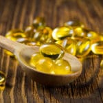 Cod-liver oil, omega3, vitamin D capsules on wooden spoon