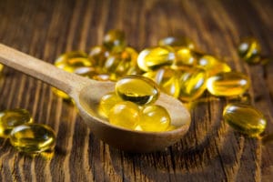 Cod-liver oil, omega3, vitamin D capsules on wooden spoon