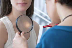 Oncologist examining female patient with magnifier in clinic