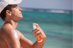 man in the beach spraying sunscreen