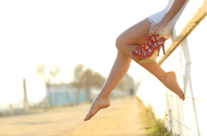 Woman legs silhouette with high heels sitting on a wall
