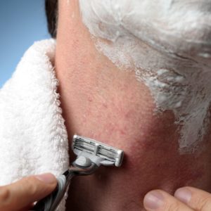 man shaving with razor and towel and razor burn and bumps