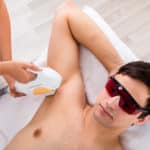 High Angle View Of A Therapist Giving Laser Epilation Treatment On Man's Armpit