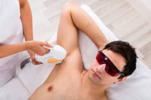 High Angle View Of A Therapist Giving Laser Epilation Treatment On Man's Armpit